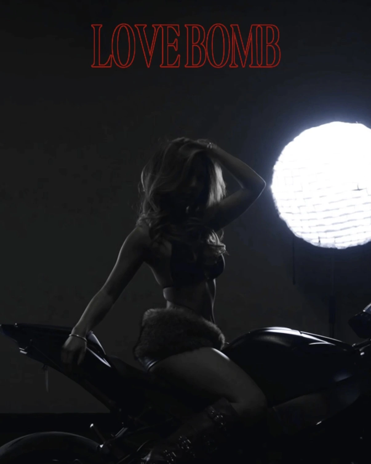 miinii silhouetted on a motorcycle against a circular spotlight